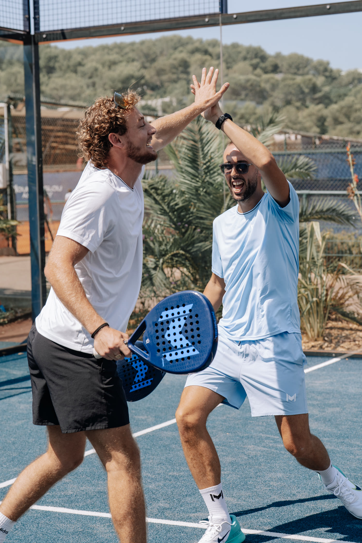 Deux joueurs se félicitant après un point sur un court de padel Mouratoglou